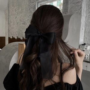 Elegant black satin bow hair clip accessory shown on model's hair for a stylish look