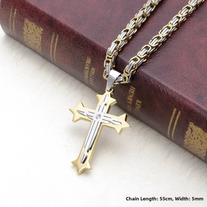 Détail d'un pendentif croix bicolore avec chaîne de 5mm sur fond de livre rouge ancien