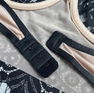 Détail de la fermeture à trois rangées sur lingerie en dentelle noire et tissu mesh
