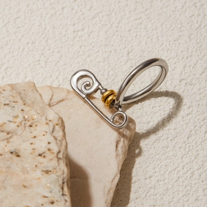 Detailed close-up of a two-tone safety pin ring in gold and silver stainless steel