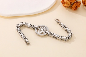Macro detail of silver stainless steel curb chain bracelet with Hamsa Hand crystal charm
