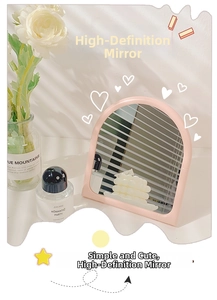 Close-up of pink wave frame tabletop mirror with artistic natural window shadows