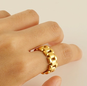 Macro shot of gold geometric link chain ring in stainless steel worn on finger