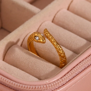 Macro detail of gold snake ring with white diamond eyes and scale texture in jewelry box