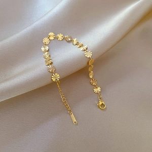 Dettaglio macro del bracciale dorato con motivo a sole e chiusura a moschettone