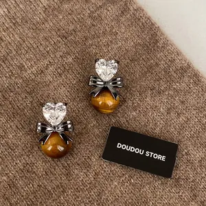 Detailed shot of tiger eye stone heart earrings on a warm brown knitted sweater