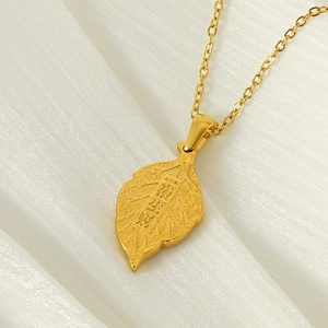 Gold leaf pendant necklace with lucky engraving on elegant ivory silk background