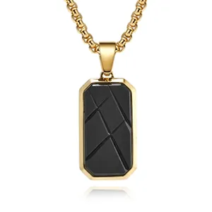 Macro view of gold box chain and black rectangular geometric pendant with subtle reflection