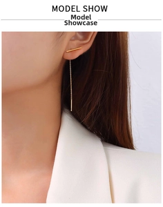 Close-up of minimalist 18k gold vertical bar long chain earrings on model with white blazer