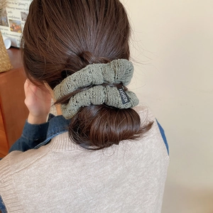 Detailed knit texture of olive green scrunchie styled on a low ponytail ponytail hair tie