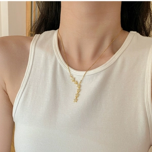 Close-up of gold titanium steel necklace with shimmering star tassels on collarbone