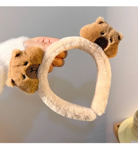 Close-up of soft plush beige headband with cute brown stuffed bear decorative elements