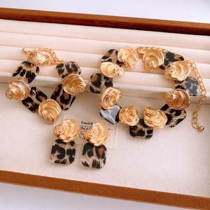 Detail of gold metal and leopard print resin jewelry set including earrings and bracelet