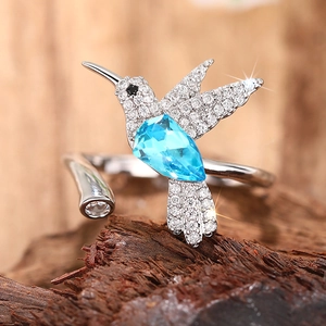 Macro-opname van zilveren kolibrie-ring met blauwe edelsteen op een natuurlijk houtblok