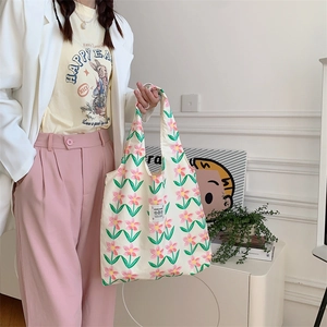 Borsa tote in tela a fiori rosa portata da una modella con un abbigliamento casual