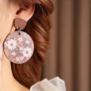 Vintage wooden round earrings with purple floral patterns worn by a model on dark background