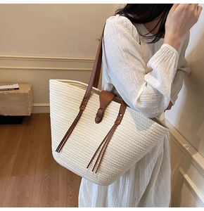 Lifestyle view of a large woven tote bag with brown leather straps worn by a model
