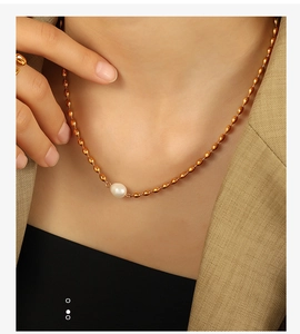 Close-up of elegant gold beaded chain necklace with a lustrous white pearl on a model