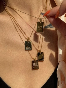 Close-up of rectangular 18k gold plated necklaces with engraved inspirational quotes