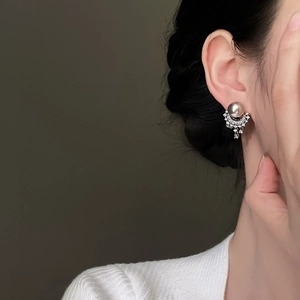 Detail view of a pearl earring with sparkling rhinestones on an elegant model's ear