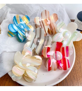 Detailed collection of floral hair claws with colorful stripes and glossy finish on a tray