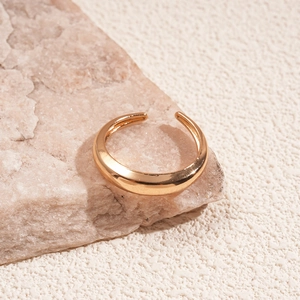 Detailed close-up of golden metallic ring with wrinkled texture on natural stone base