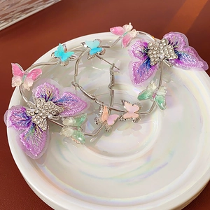 Détail de créoles argentées avec papillons brodés violets et cristaux étincelants