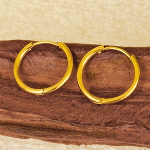 Detailed close-up of golden 304 stainless steel hoop earrings on dark wood texture