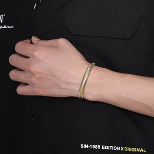 Close-up of a 18k gold-plated flat snake chain bracelet worn on a man's wrist