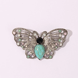 Macro shot of vintage butterfly brooch with turquoise stone and hollow silver wings