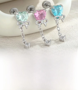 Detail of heart zircon bow cartilage studs in mint green, pink, and sky blue finishes