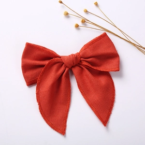 Detailed close-up of a red linen bow hair clip on a clean white background with dried flowers