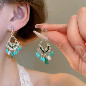 Bohemian gold tassel earrings with turquoise beads and crystals worn by a model