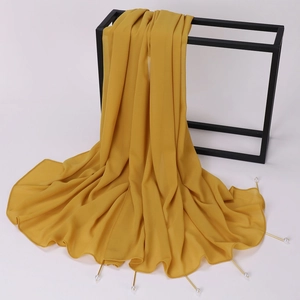 Detail of yellow chiffon shawl with gold tube and pearl pendants on black metal frame