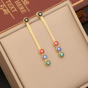 Detail of gold evil eye tassel earrings with colorful enamel charms on a jewelry box