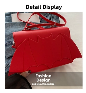 Detail of red bat-wing crossbody bag in matte faux leather over a denim jacket
