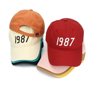 Detailed stack of multi-color cotton baseball caps featuring 1987 embroidery and metal buckles