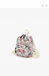 Detailed side view of mini canvas backpack featuring a vintage floral print on cream fabric