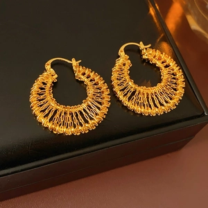 Détail de boucles d'oreilles créoles tressées dorées sur une boîte à bijoux noire