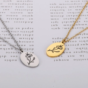 Detailed view of oval floral engraved pendants in gold and silver on a minimalist background
