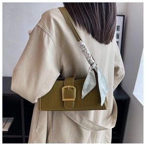 Detail of olive green crocodile textured handbag with golden square buckle and silk scarf
