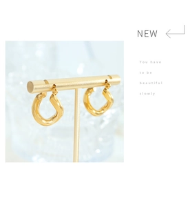 Close-up of twisted 18k gold-plated titanium earrings on a T-shaped jewelry display stand