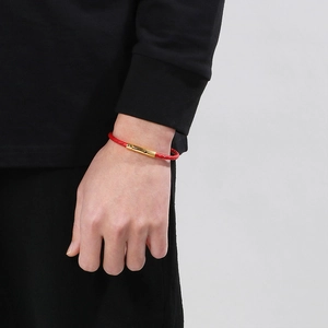 Gros plan d'un bracelet tressé rouge avec fermoir magnétique en acier doré poli