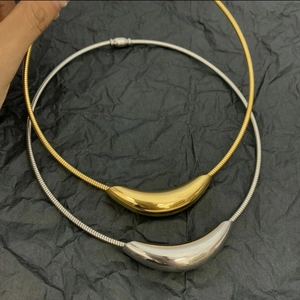 Macro shot of minimalist gold and silver titanium curved bar pendants on snake chains