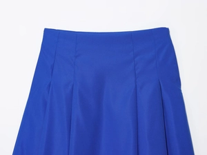 Détail macro de la jupe midi plissée bleu roi montrant la taille et la texture du tissu
