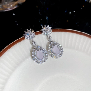 Détail des boucles d'oreilles fleur goutte en argent avec pierres lavande sur céramique