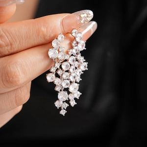 Macro shot of silver tassel earrings with layered zircon crystals held by hand