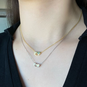 Close-up of gold and silver S925 necklaces with heart and E letter pendants on neck