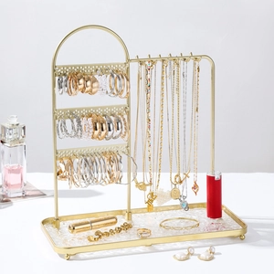 Golden iron jewelry display stand with necklace hooks and textured tray for storage
