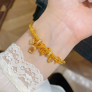 24k gold-plated flower bracelet with clover charms and oval stones on a woman's wrist